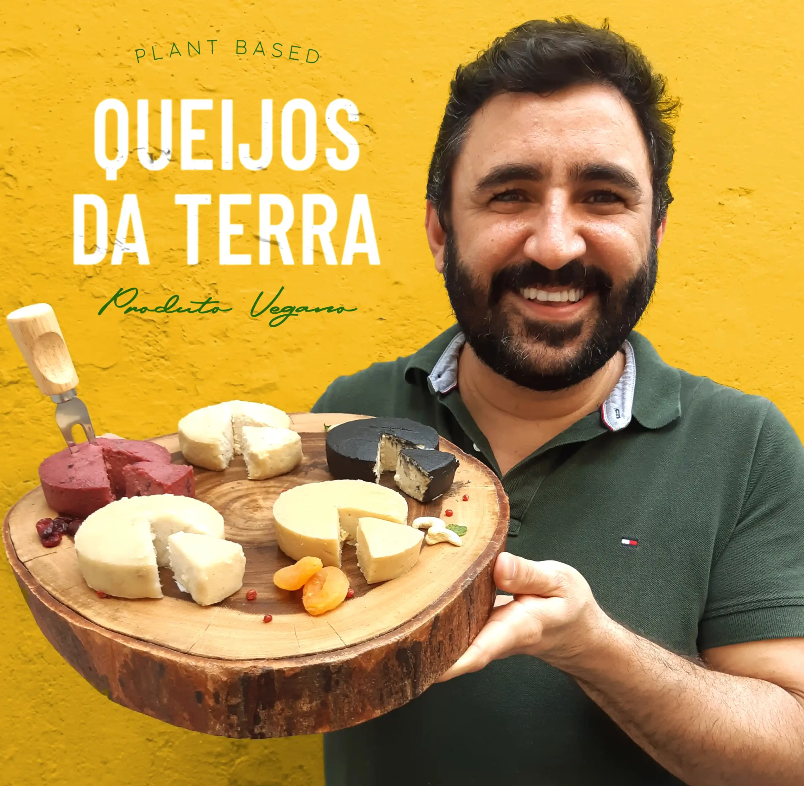 Ton Daltro, fundador da Queijos da Terra, sorrindo enquanto segura uma tábua de madeira com os cinco Queijos de Corte. Ao fundo, parede amarela com o logo da Queijos da Terra.