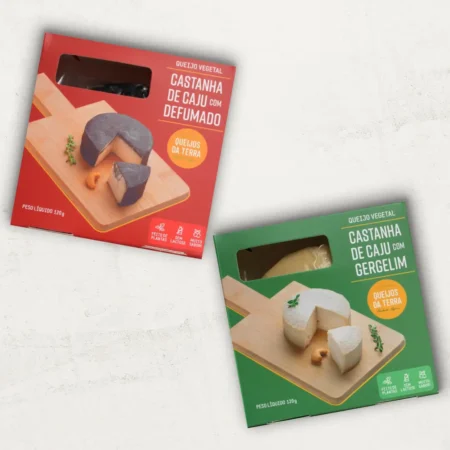 O kit contém 2 Queijos de Castanha de Caju: 1 Queijo de Castanha de Caju Defumado e 1 Queijo de Castanha de Caju com Gergelim. Uma embalagem vermelha e uma verde.