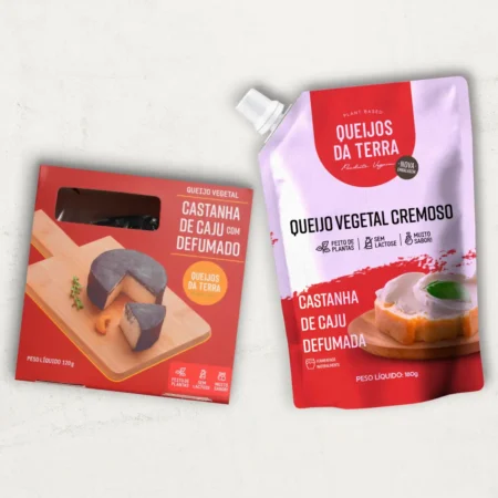 O kit contém 2 Queijos de Castanha de Caju: 1 Queijo de Castanha de Caju Defumado e 1 Queijo de Castanha de Caju Cremoso Defumado, em embalagem tipo pouch. Ambos vêm em embalagens vermelhas.