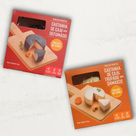 O kit contém 2 Queijos de Castanha de Caju: 1 Queijo de Castanha de Caju Defumado e 1 Queijo de Castanha de Caju Trufado com Damasco. Uma embalagem vermelha e uma laranja.