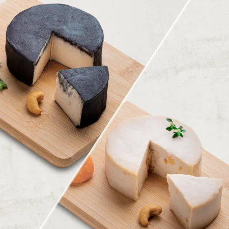 O kit contém 2 Queijos de Castanha de Caju: 1 Queijo de Castanha de Caju Defumado e 1 Queijo de Castanha de Caju Trufado com Damasco. Os queijos são fotografados de lado.